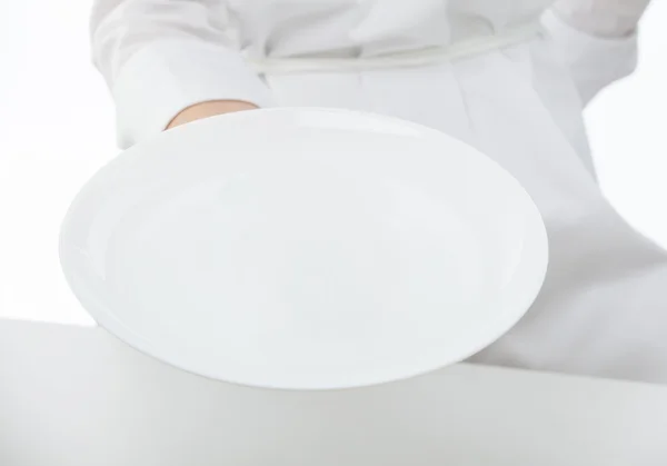 Μαγείρων χέρι που κρατά το άσπρο πιάτο — Φωτογραφία Αρχείου