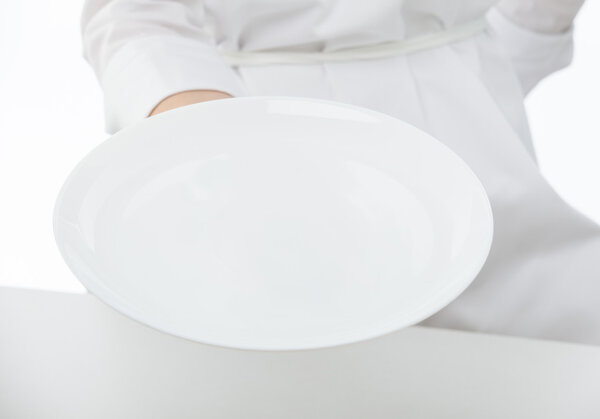 Cook's hand holding white plate