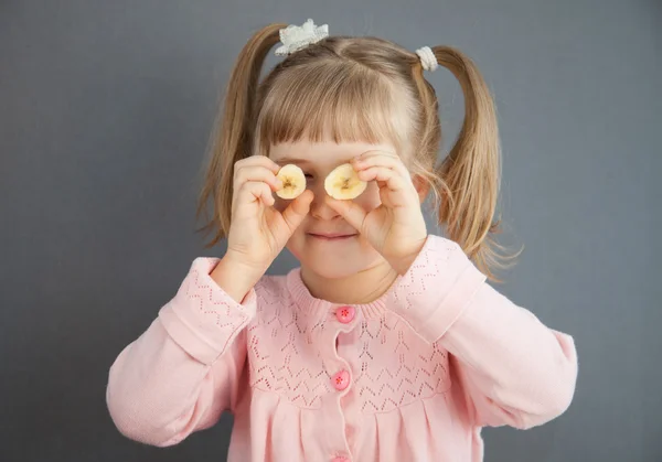 Encantadora niña jugando con trozos de un plátano maduro — Foto de Stock