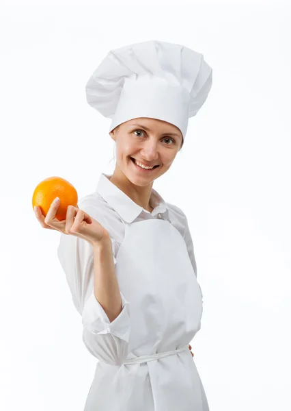 Beautiful young female cook showing an orange — Stock Photo, Image