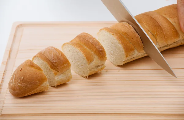 Cutting bread on wooden board — Stock Photo, Image