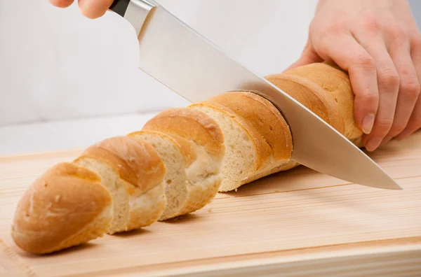 Cutting bread on wooden board — Stock Photo, Image