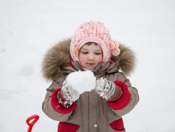 小さな女の子が雪玉で遊んで — ストック写真