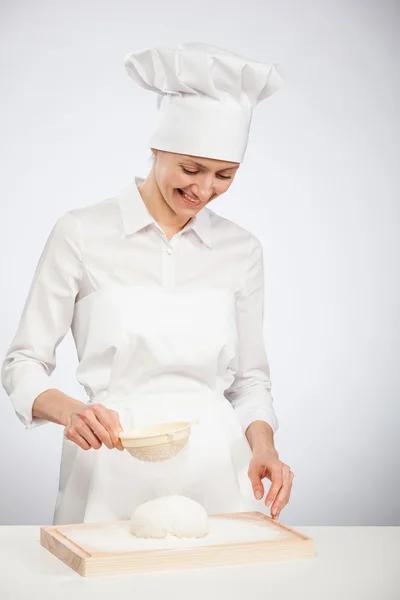 Mladá žena vařit přepudrovat těsta s moukou na dřevěné desce — Stock fotografie
