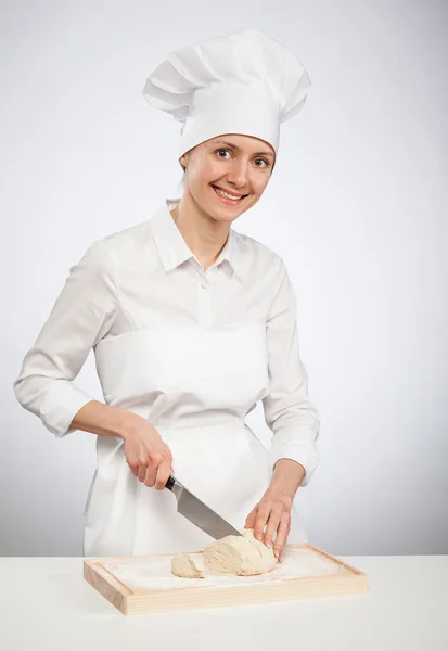 Mulher cozinheiro cortar massa crua na farinha com uma faca — Fotografia de Stock