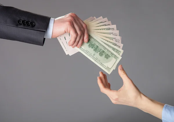 Human hands passing fan of dollar banknotes — Stock Photo, Image