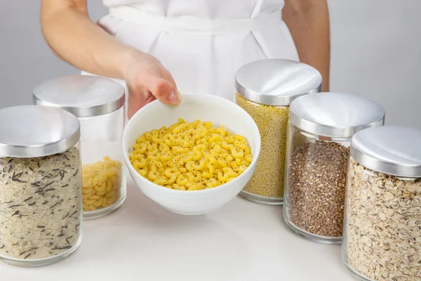 Vrouwelijke handen met een kom met ruwe macaroni — Stockfoto