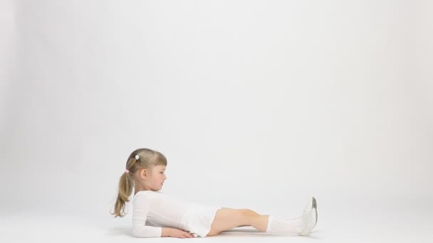 Linda niña tendida en el suelo y haciendo ejercicio — Vídeo de stock