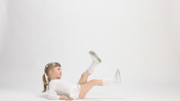 Linda niña tendida en el suelo y haciendo ejercicio — Vídeo de stock