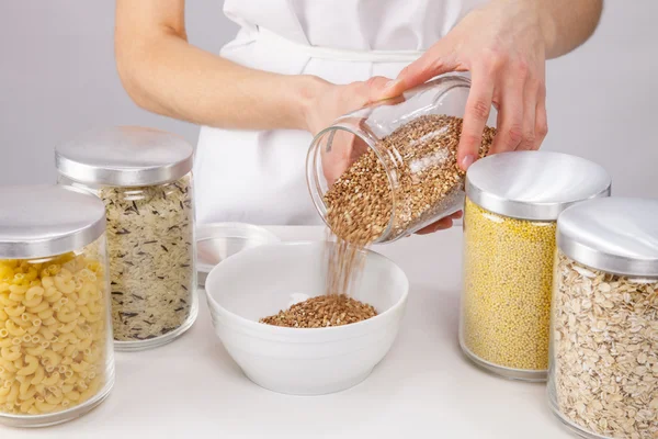 Weibliche Hände halten einen Topf mit rohem Buchweizen — Stockfoto