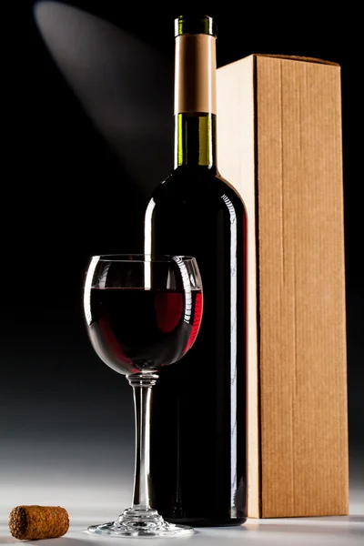 Wine bottle with box and filled glass of wine — Stock Photo, Image