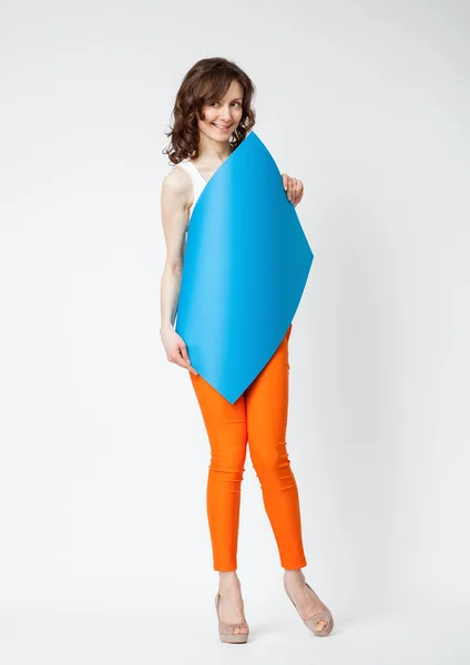 Speelse jonge vrouw in oranje broek blauw papier bedrijf — Stockfoto