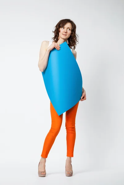 Piękna młoda kobieta w pomarańczowe spodnie, trzymając papier niebieski — Zdjęcie stockowe