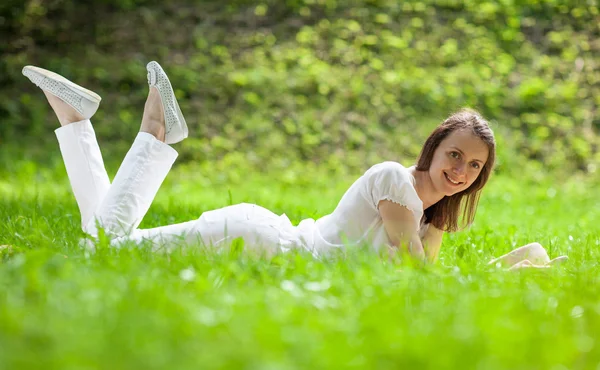 Šťastná mladá žena leží na zelené trávě — Stock fotografie