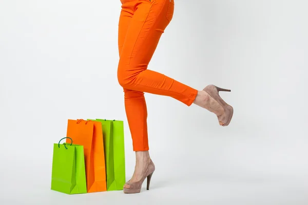 Ženské nohy v oranžové kalhoty a nákupní tašky — Stock fotografie
