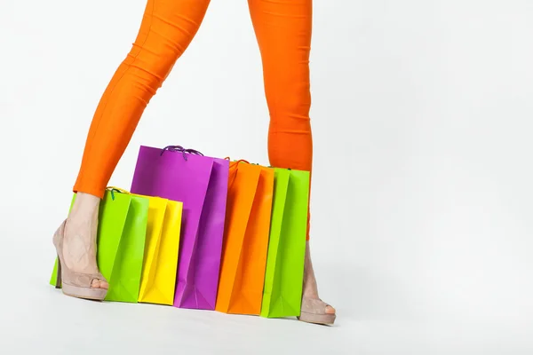 Vrouw benen in oranje broek en shopping tassen — Stockfoto