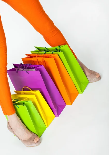 Pernas de mulher em calças laranja e sacos de compras — Fotografia de Stock