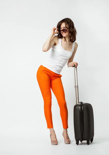 Playful young woman in orange pants with suitcase — Stock Photo, Image