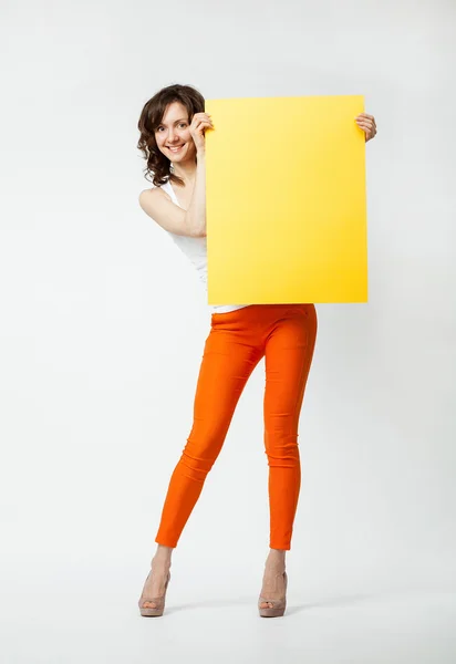 Joyful young woman holding blank yellow placard — Stock Photo, Image