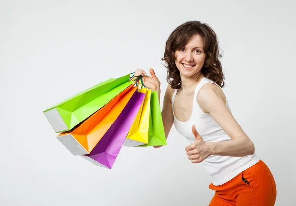 Mulher com sacos de compras segurar a mão com o polegar para cima gesto — Fotografia de Stock