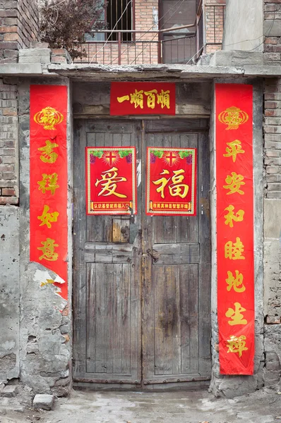 Puerta china de madera vieja con carteles de fortuna pelando — Foto de Stock