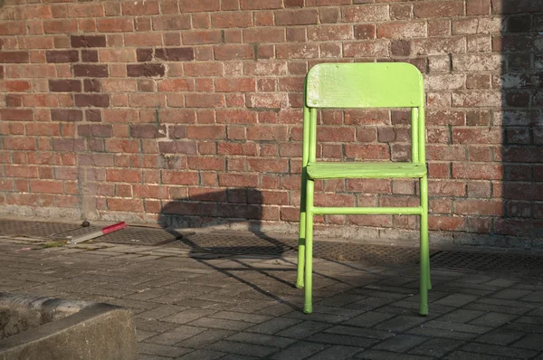 Old green chair next to an outdoor brick wall — Stock Photo, Image