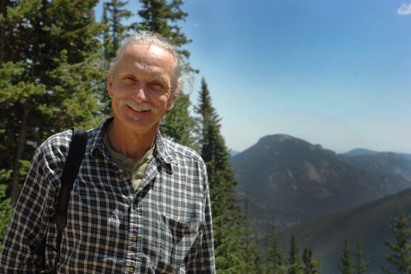 Smiling middle aged man near trees, mountains
