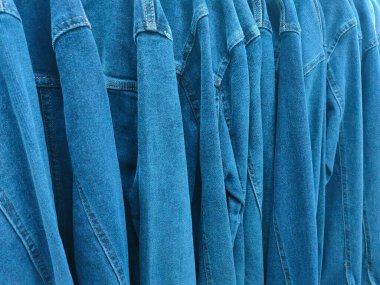 Mağazadaki askılarda asılı mavi kot gömleklerin arka planı