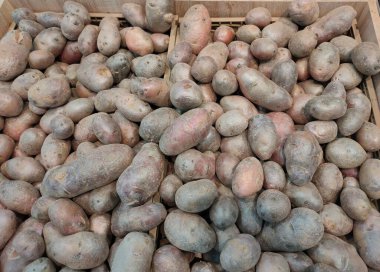 Kırmızı patatesleri süpermarket tezgahındaki tahta kutularda yıkadım.