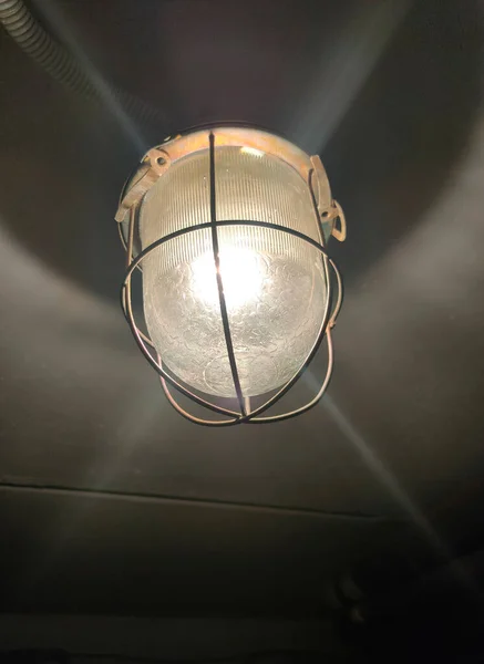 Oude Plafondlamp Met Beschermende Grille Gloeiend Een Donkere Kelder — Stockfoto