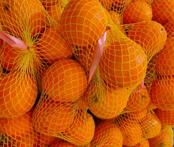 新鲜橙子 用聚丙烯黄色网装在商店柜台上 — 图库照片
