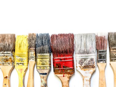 Used and dried paint brushes laid in a row shot from above on white