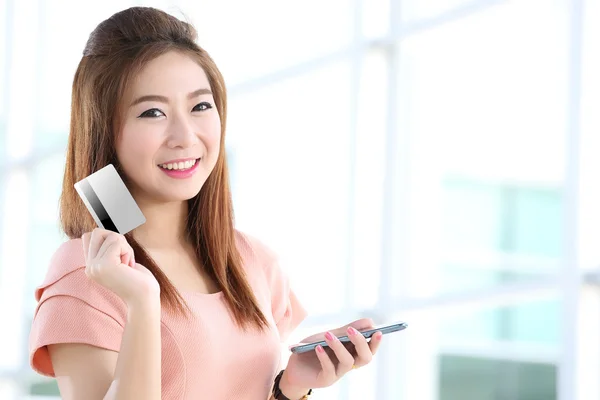 Женщина показывает кредитную карту после оплаты с мобильного телефона — стоковое фото