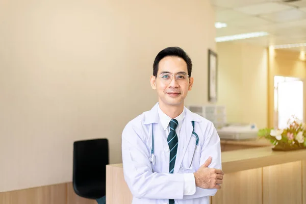 病院に立ちながら聴診器で眼鏡をかけたアジア系男性医師の肖像 — ストック写真