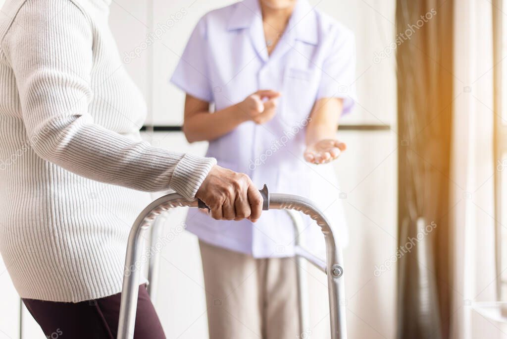 Nurse helping senior woman hand holding walker trying to walk,Care nursing home concept