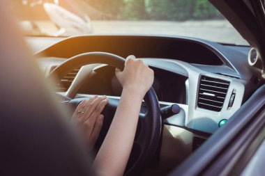 Hands of female driver on steering wheel,Woman driving a car on road