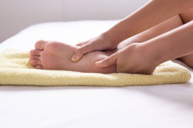 Kadın elleri yatak odasında ayaklarına masaj yapıyor.