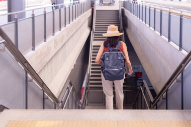 Tren istasyonunda merdivenlerde yürüyen kadın yolcu, ulaşım sigortası konsepti