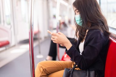 Metro treninde cep telefonu kullanan kadın yolcu, seyahat sigortası kavramı