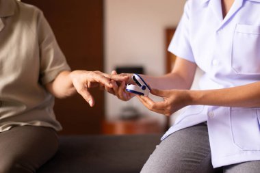 Hemşire parmak ucu nabız oksimetre oksijen doygunluk ölçer SPO2 PR kan monitörü parmağı orta yaşlı hasta kadın, evde bakım servisi