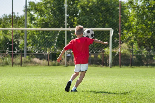 Мальчик пинает футбола — стоковое фото