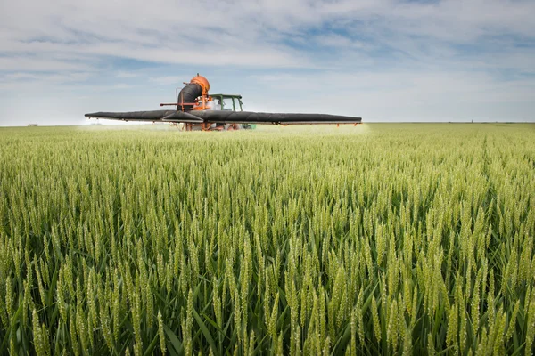 Trekker spuiten op het veld — Stockfoto