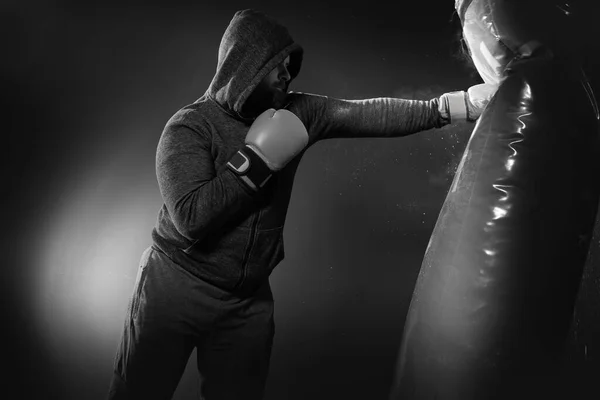 Boxer hits punching bag. Young boxer trains on punching bag.