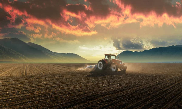 Farmer with tractor seeding - sowing crops at agricultural field. Plants, wheat.