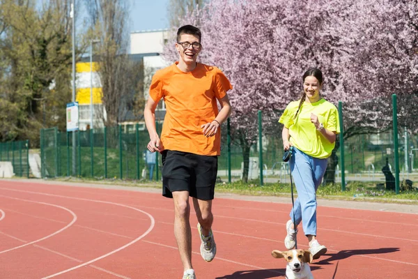 Młoda Szczęśliwa Para Biegająca Sportowym Szlaku Psem — Zdjęcie stockowe