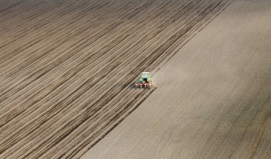 Traktör tohumu olan çiftçi - ilkbaharda tarım tarlalarına ekin ekiyor.