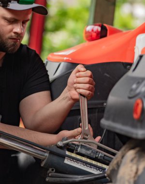 Çiftçi tarladaki tarım makinelerini tamir ediyor. 