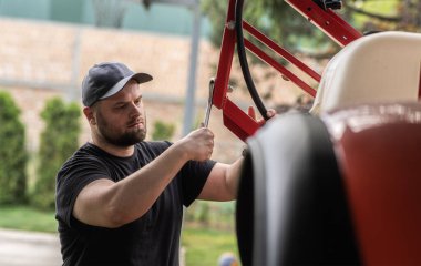 Çiftçi tarladaki tarım makinelerini tamir ediyor. 