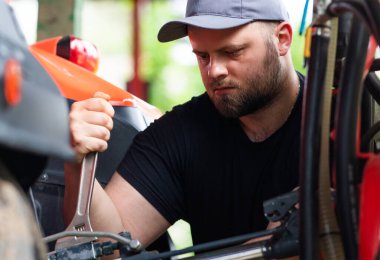 Çiftçi tarladaki tarım makinelerini tamir ediyor. 