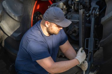 Çiftçi tarladaki tarım makinelerini tamir ediyor. 